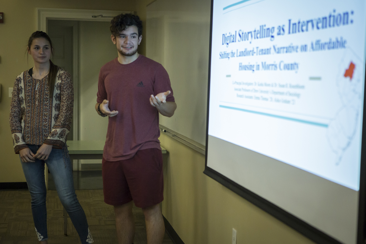 A woman and man standing next to a project screen