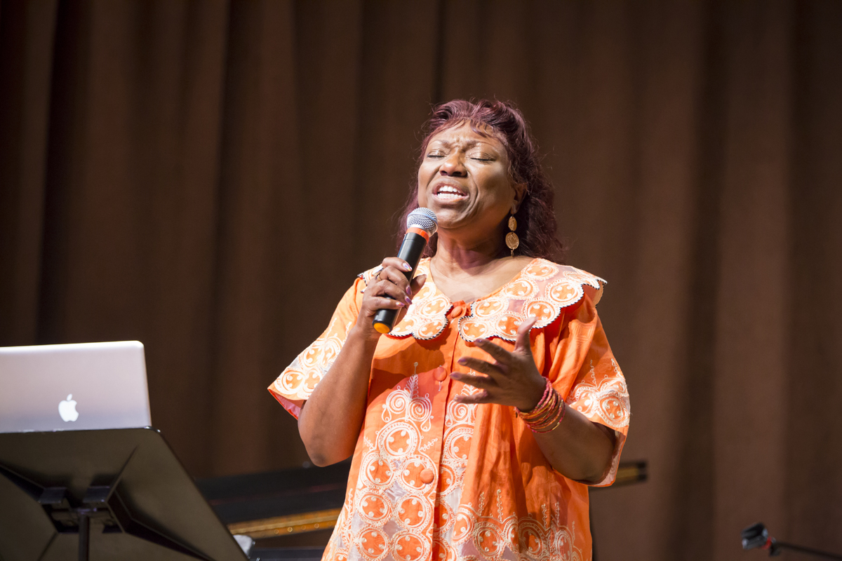 Cynthia Wilson singing into a microphone with her eyes closed