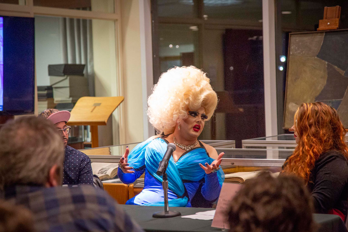 Drag artist Pissi Myles speaks while seated at a table