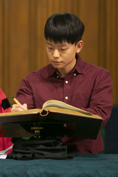Male student signs matriculation book.